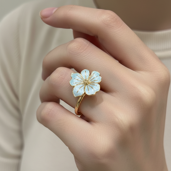 Anillo ajustable con flor esmaltada azul claro y baño de oro 18K en mano de modelo