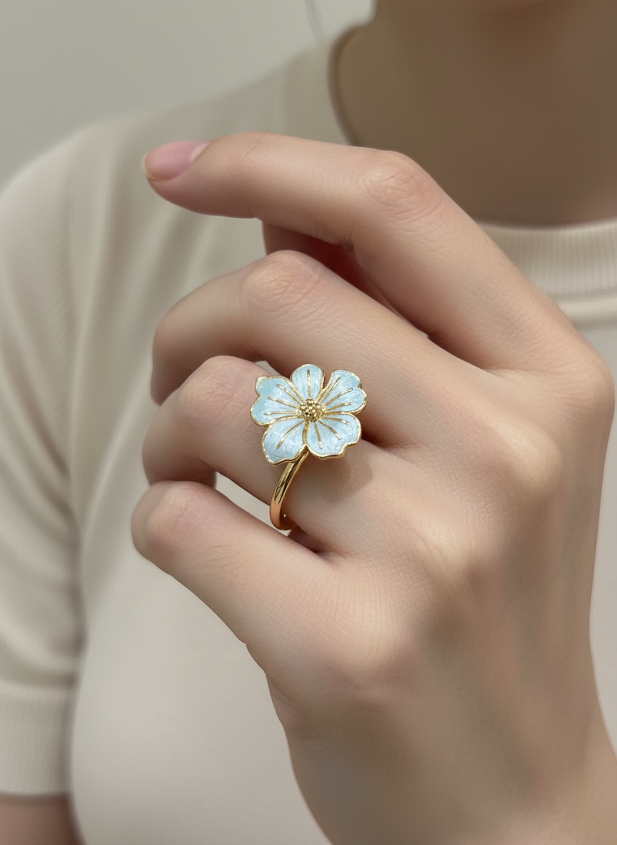 Anillo ajustable con flor esmaltada azul claro y baño de oro 18K en mano de modelo