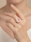 Anillo ajustable con flor esmaltada rosa palo y baño de oro 18K en mano de modelo