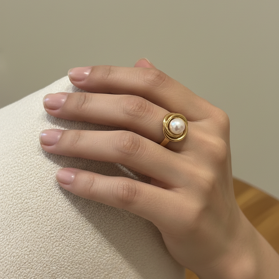Anillo nudo de perla en acero con baño de oro 18K en mano de modelo