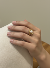Anillo nudo de perla en acero con baño de oro 18K en mano de modelo