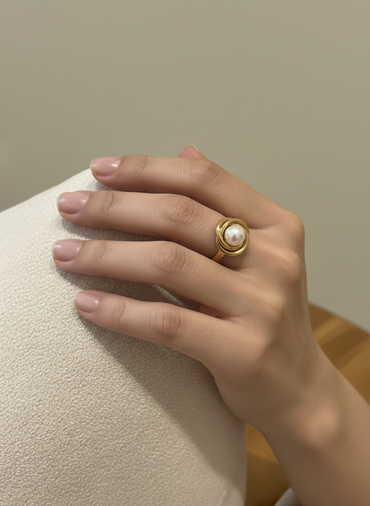 Anillo nudo de perla en acero con baño de oro 18K en mano de modelo