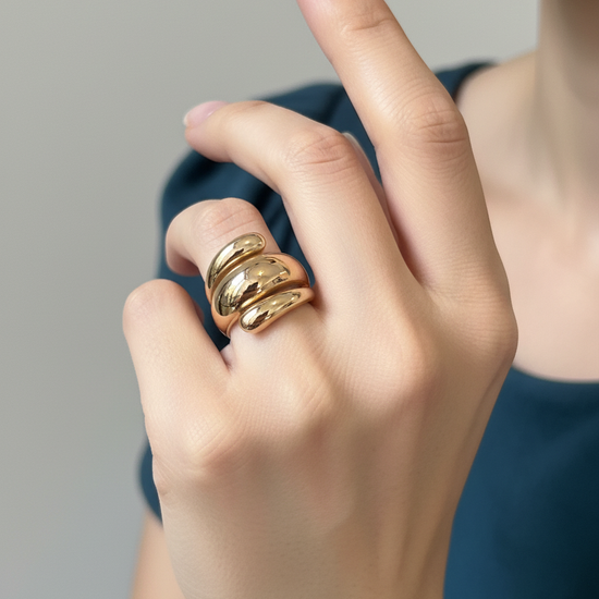 Anillo de acero con baño de oro 18K de tres volúmenes tipo “ola” (talla 8) en mano de modelo