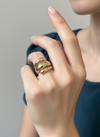 Anillo de acero con baño de oro 18K de tres volúmenes tipo “ola” (talla 8) en mano de modelo