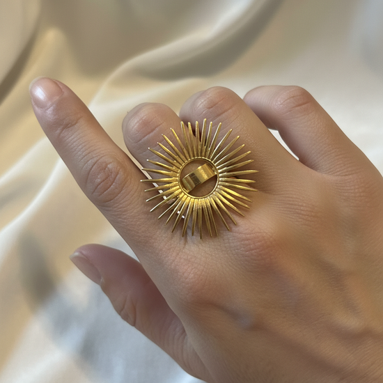 Anillo ajustable de acero con baño de oro 18K en forma de sol radiante en mano de modelo