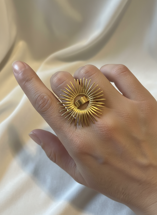Anillo ajustable de acero con baño de oro 18K en forma de sol radiante en mano de modelo
