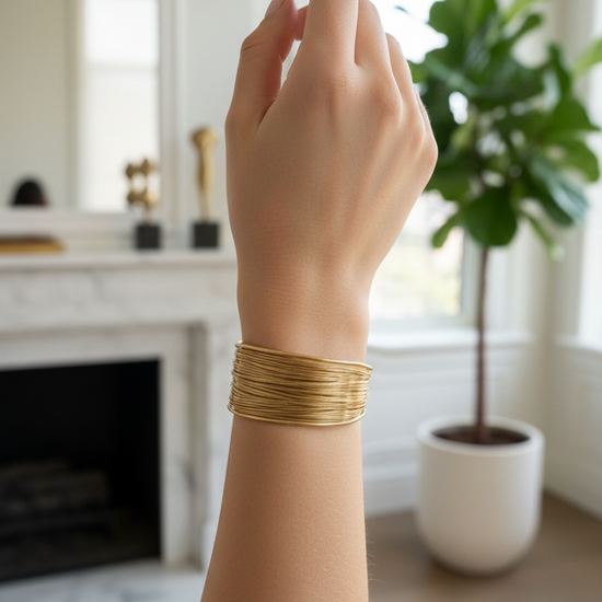 Brazalete ancho abierto efecto hilos dorados en acero con baño de oro 18K sobre modelo