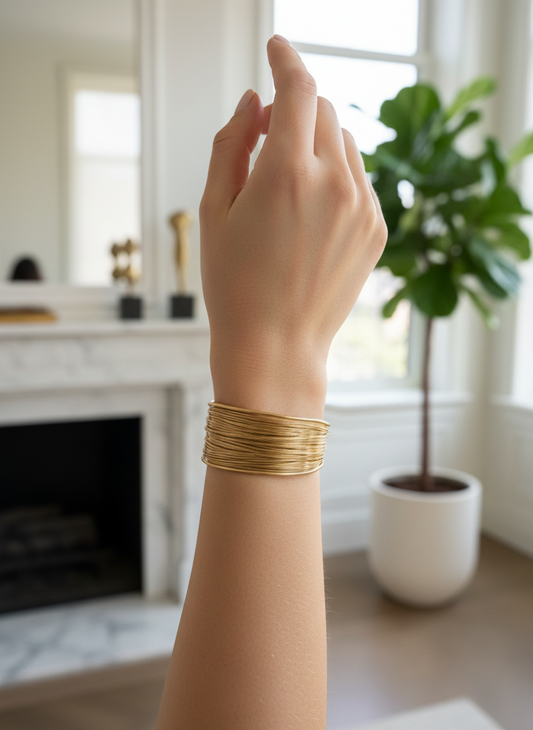 Brazalete ancho abierto efecto hilos dorados en acero con baño de oro 18K sobre modelo