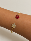 Pulsera Dúo Floral Encantado BRAVATA, detalle 2: pulsera rígida abierta con dos flores en los extremos; una flor con cinco pétalos rojos facetados y centro dora