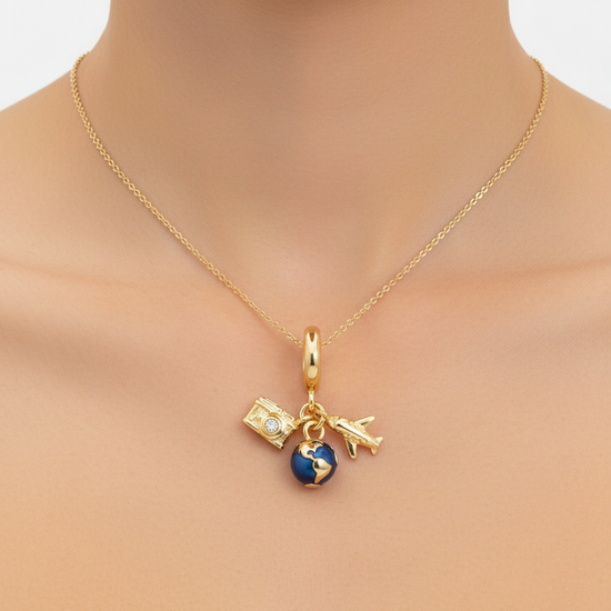 Charm dorado con globo azul, cámara con circonita y avión en acero con baño de oro 18K sobre modelo
