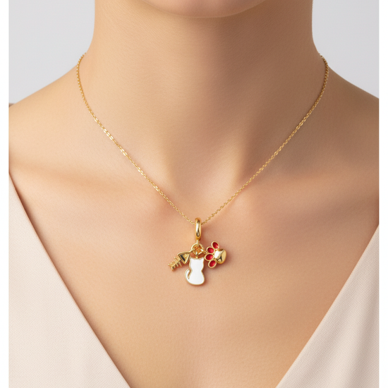 Charm dorado con gato blanco, huella roja y espina de pez en acero con baño de oro 18K sobre modelo