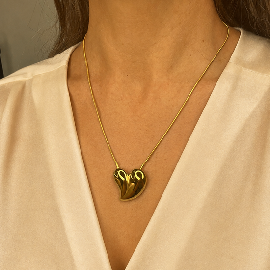 Mujer llevando el Collar Avelon dorado con colgante de corazón irregular.