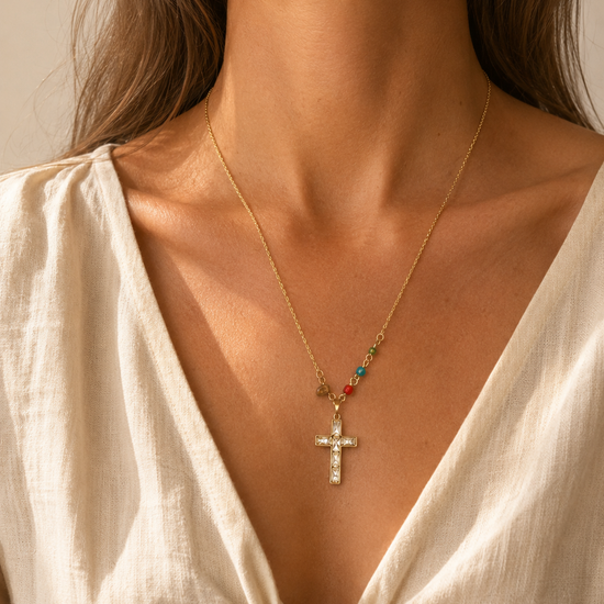 Mujer llevando el Collar Calista dorado con cruz de cristales y pequeñas cuentas de colores.