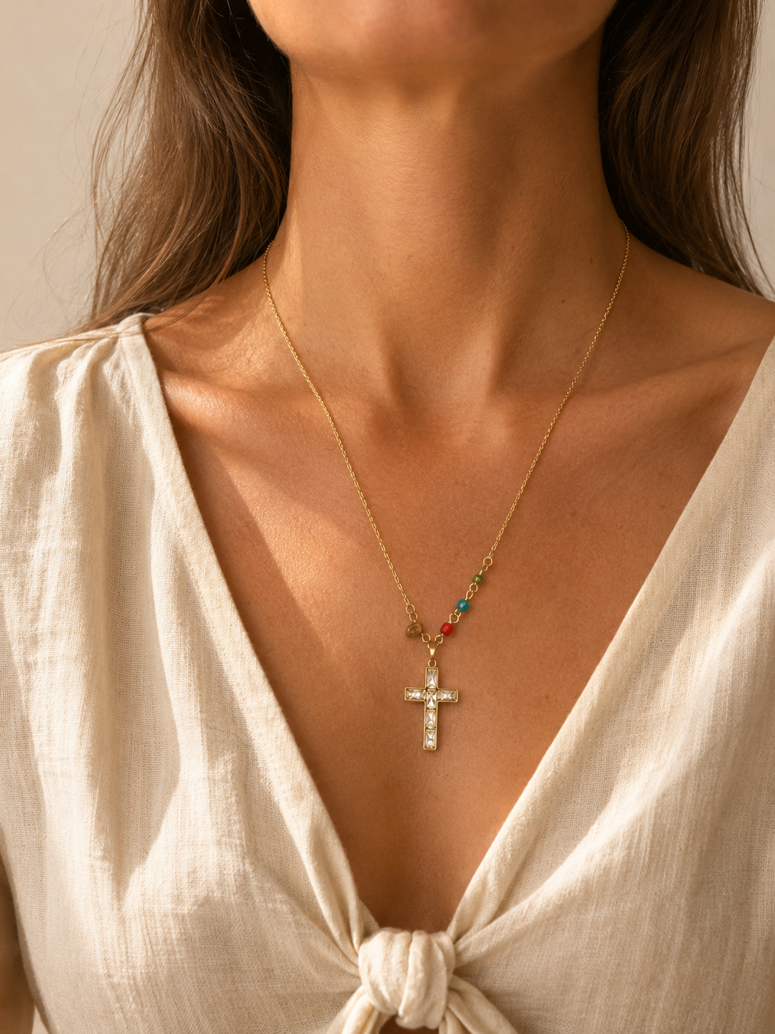 Mujer llevando el Collar Calista dorado con cruz de cristales y pequeñas cuentas de colores.