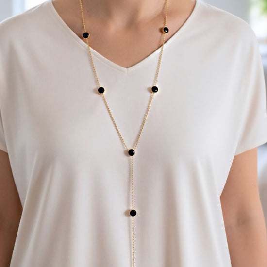 Collar lariat dorado con discos negros esmaltados en acero con baño de oro sobre modelo