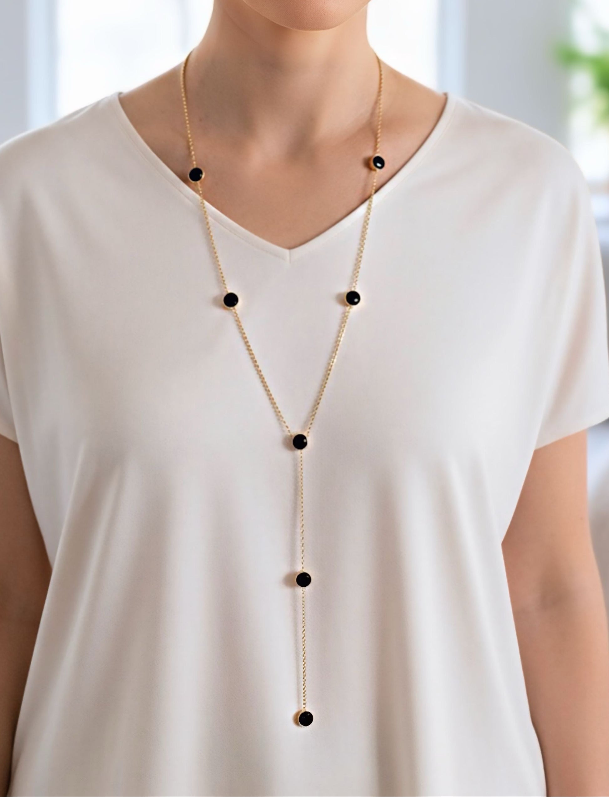Collar lariat dorado con discos negros esmaltados en acero con baño de oro sobre modelo
