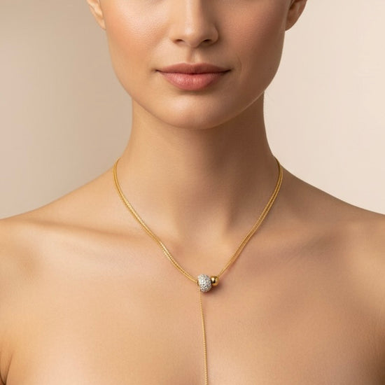 Collar lariat dorado con cuenta pavé y terminal esférico en acero con baño de oro 18K sobre modelo
