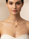 Collar lariat dorado con cuenta pavé y terminal esférico en acero con baño de oro 18K sobre modelo