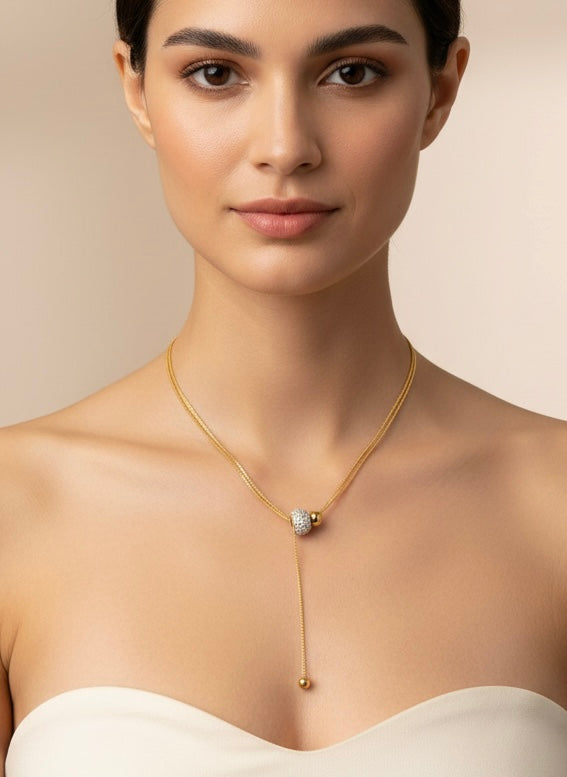 Collar lariat dorado con cuenta pavé y terminal esférico en acero con baño de oro 18K sobre modelo