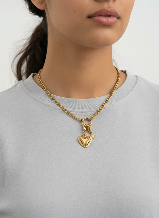 Collar Love dorado en acero inoxidable con colgante de corazón grabado y cierre en aro decorativo sobre modelo