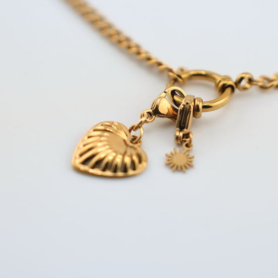 Detalle de Collar Love dorado en acero inoxidable con colgante de corazón grabado y cierre en aro decorativo