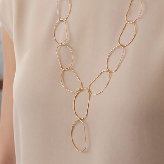 Collar largo dorado de óvalos abiertos con caída en Y y cierre regulable sobre modelo