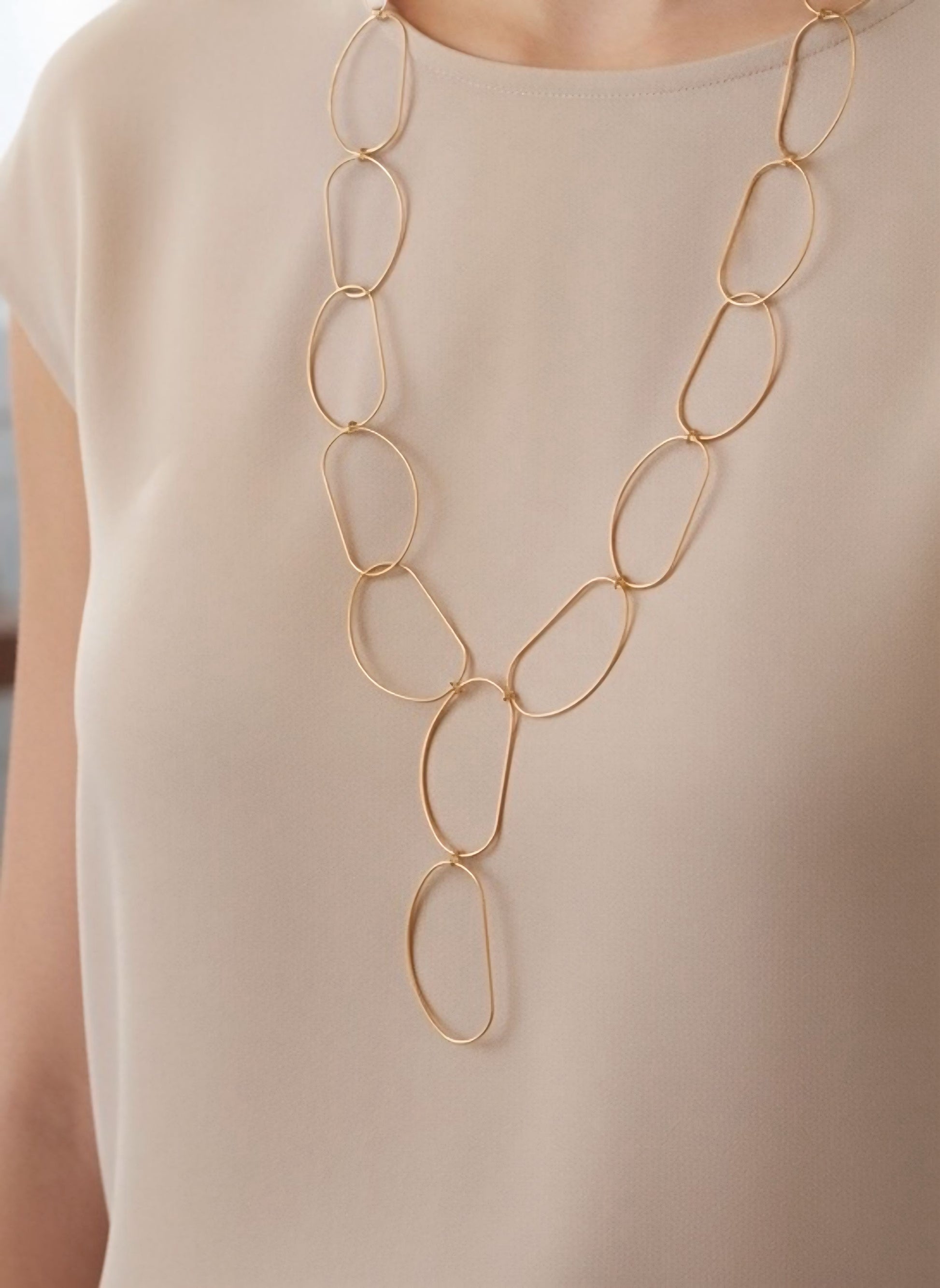 Collar largo dorado de óvalos abiertos con caída en Y y cierre regulable sobre modelo