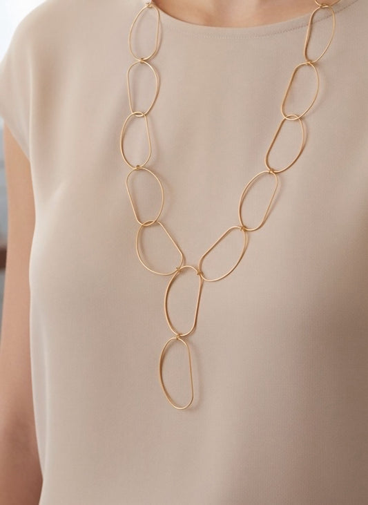 Collar largo dorado de óvalos abiertos con caída en Y y cierre regulable sobre modelo