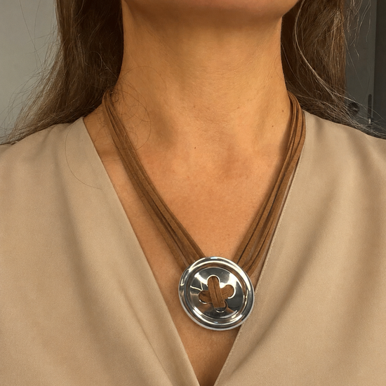 Mujer llevando el Collar Sorelia marrón multicordón con pieza circular plateada.