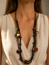 Mujer llevando el Collar Tavira marrón multicapa con cuentas oscuras y detalles efecto ámbar.