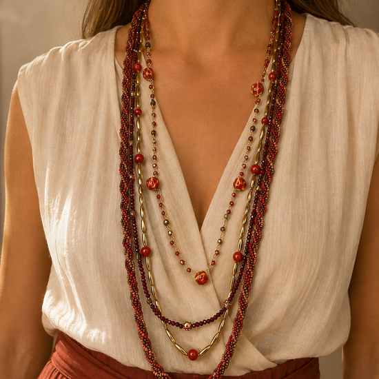Mujer llevando el Collar Varda rojo multicapa con cuentas y detalles dorados.