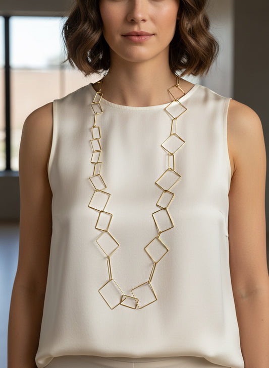 Collar largo dorado de eslabones geométricos calados en forma de rombos y cuadrados sobre modelo