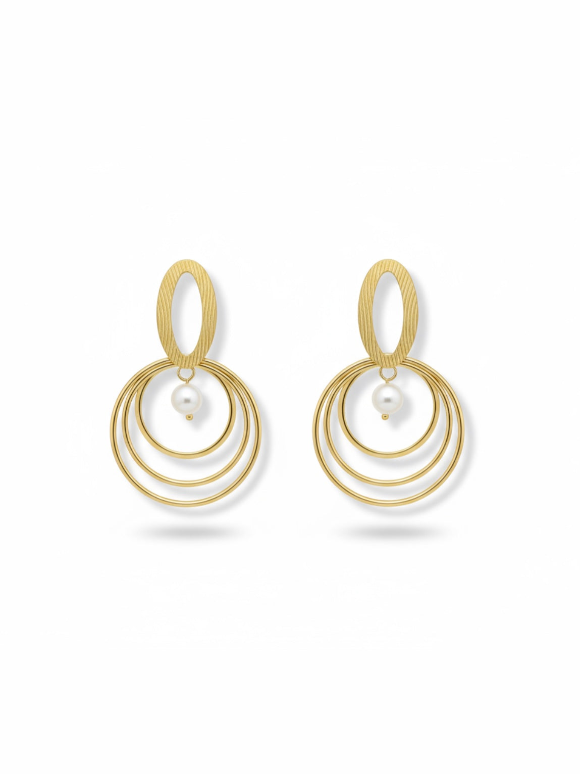 Pendientes dorados con triple aro concéntrico y perla blanca; pieza superior oval texturada (modelo Armonía Perla)