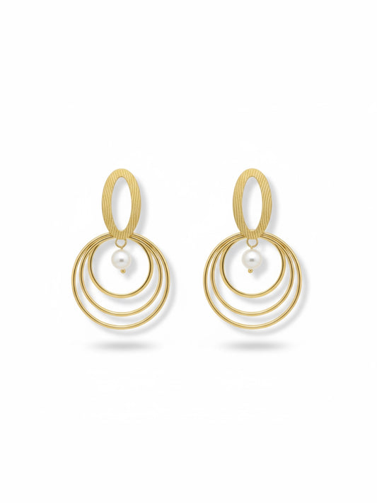 Pendientes dorados con triple aro concéntrico y perla blanca; pieza superior oval texturada (modelo Armonía Perla)