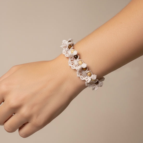 Pulsera crochet hecha a mano en coral o blanco con piedras naturales y acero dorado sobre modelo