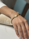 Pulsera Bravata de cordón arena con tortuga dorada y esmalte blanco expuesta en modelo