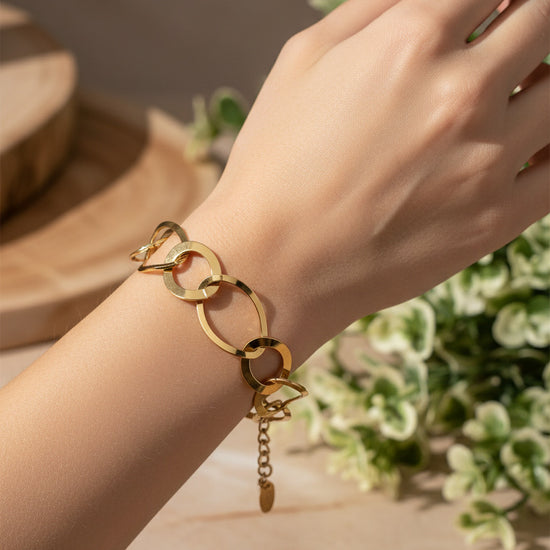 Pulsera de aros grandes dorados con acabado espejo en acero con baño de oro 18K sobre modelo