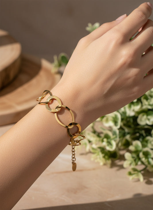 Pulsera de aros grandes dorados con acabado espejo en acero con baño de oro 18K sobre modelo