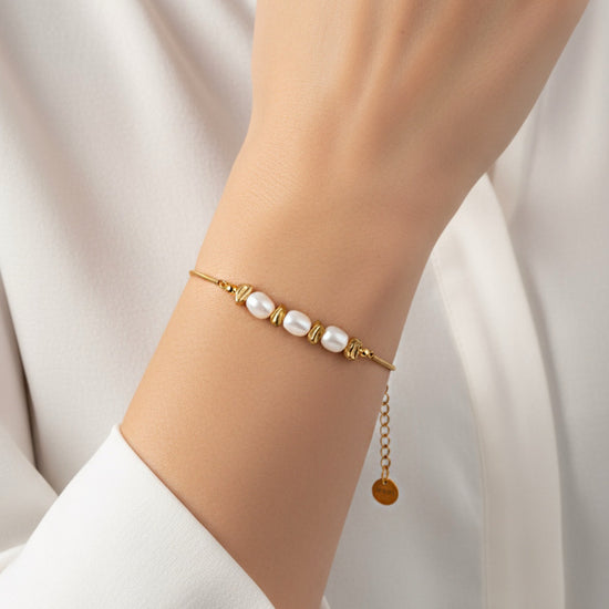 Pulsera Duna dorada con perlas blancas y cuentas irregulares en acero inoxidable con baño de oro 18K sobre modelo