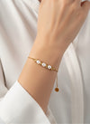 Pulsera Duna dorada con perlas blancas y cuentas irregulares en acero inoxidable con baño de oro 18K sobre modelo