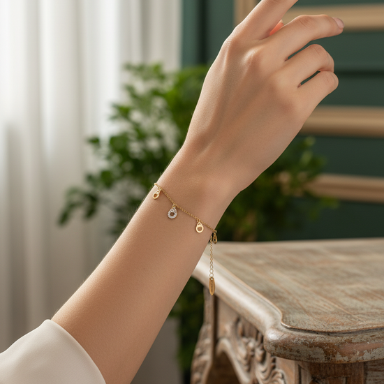 Pulsera dorada con herraduras colgantes y charm central con circonitas en acero con baño de oro 18K sobre modelo