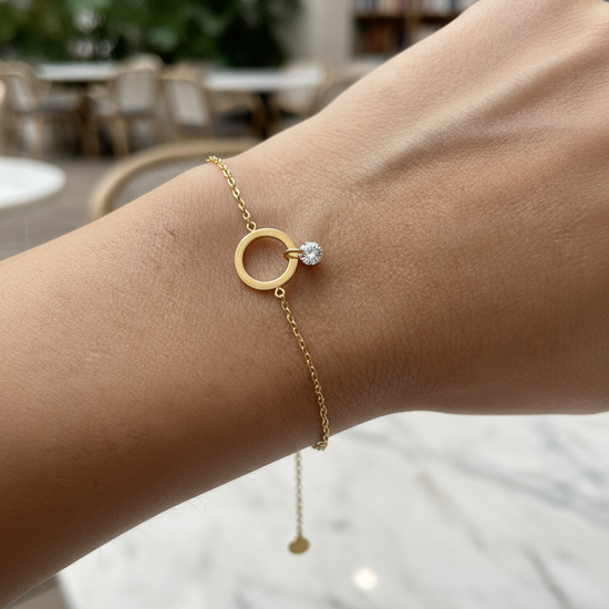 Pulsera dorada con aro central y circonita colgante, en acero con baño de oro 18K