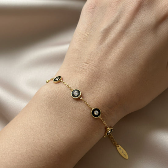 Pulsera dorada con mini discos negros y circonitas, ajustable sobre modelo