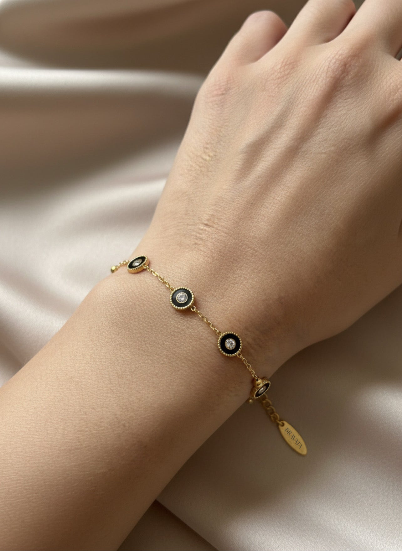 Pulsera dorada con mini discos negros y circonitas, ajustable sobre modelo