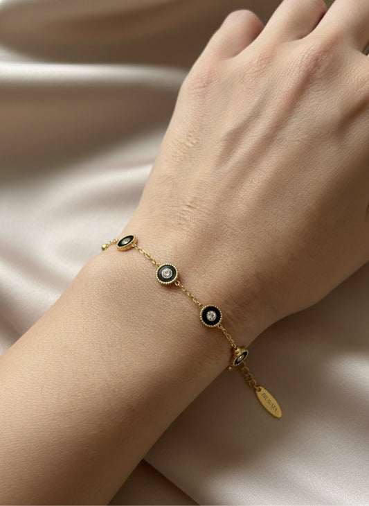Pulsera dorada con mini discos negros y circonitas, ajustable sobre modelo