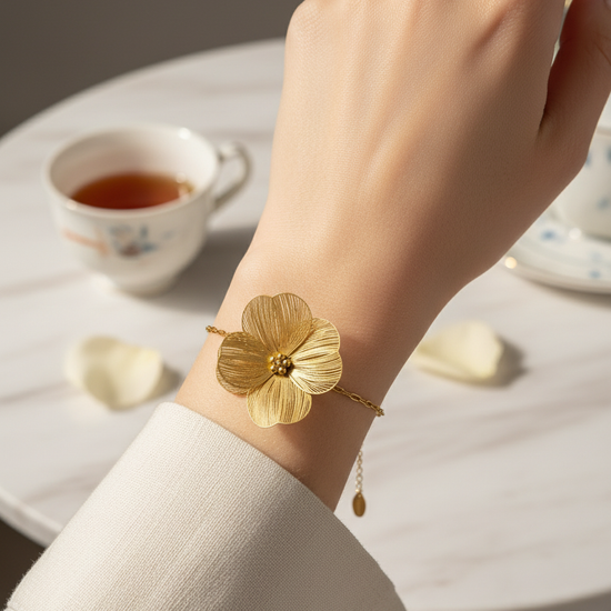 Pulsera dorada con flor grande texturada, en acero con baño de oro 18K sobre modelo