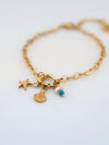Pulsera Sueños de Sal dorada con charms (estrella de mar, concha y perla con cuenta turquesa) en acero inoxidable con baño de oro 18K