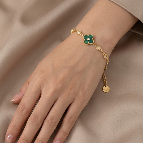 Pulsera dorada con detalle central de flor verde y circonitas brillantes, diseño delicado y elegante ideal para ocasiones especiales.