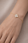 Pulsera dorada fina con detalle de trébol blanco y circonita central, diseño elegante y delicado para el día a día