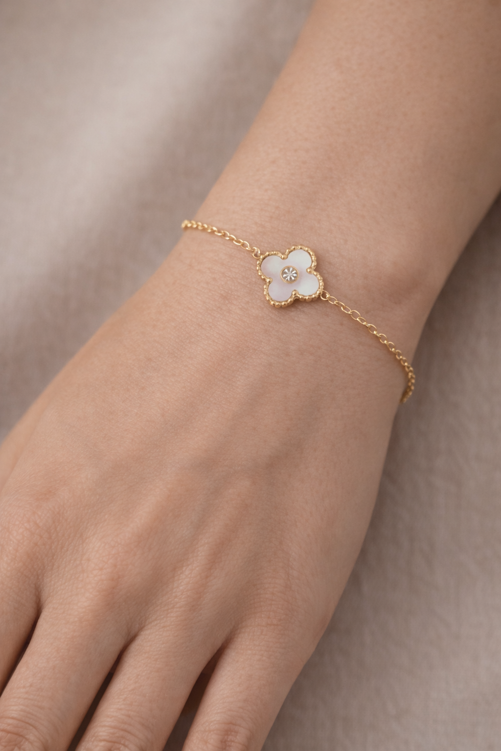 Pulsera dorada fina con detalle de trébol blanco y circonita central, diseño elegante y delicado para el día a día